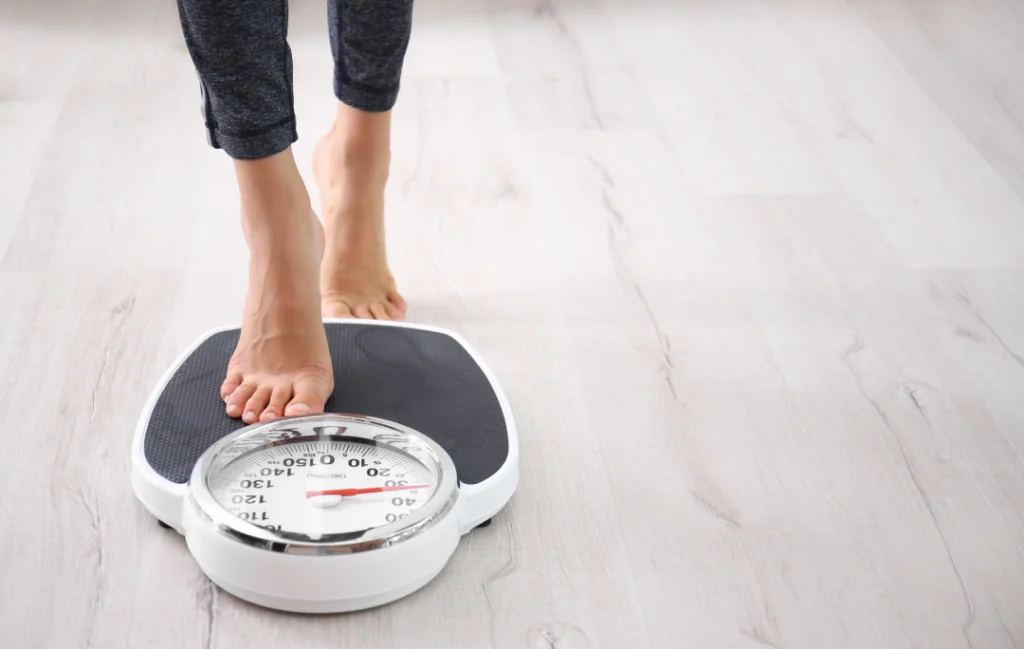 A person stepping on a weighing scale to track weight loss progress with Tirzepatide.